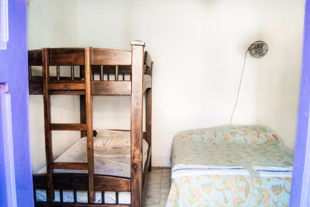 Habitacion amplia para 5 personas con ventilador y baño al frente con agua caliente.