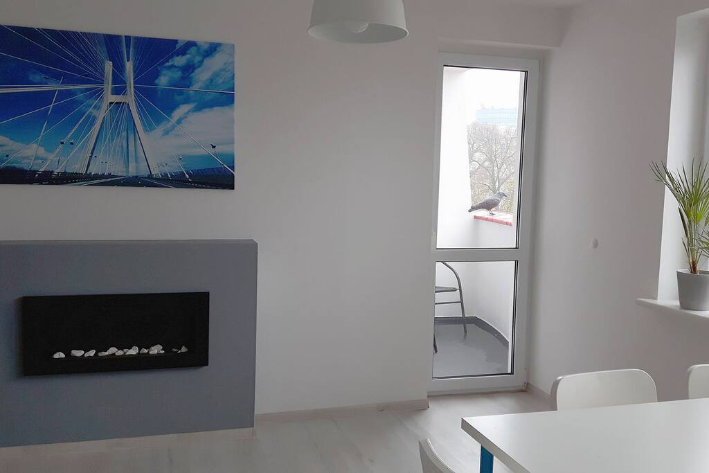 W części wspólnej znajduje się elektryczny kominek oraz wyjście na balkon.