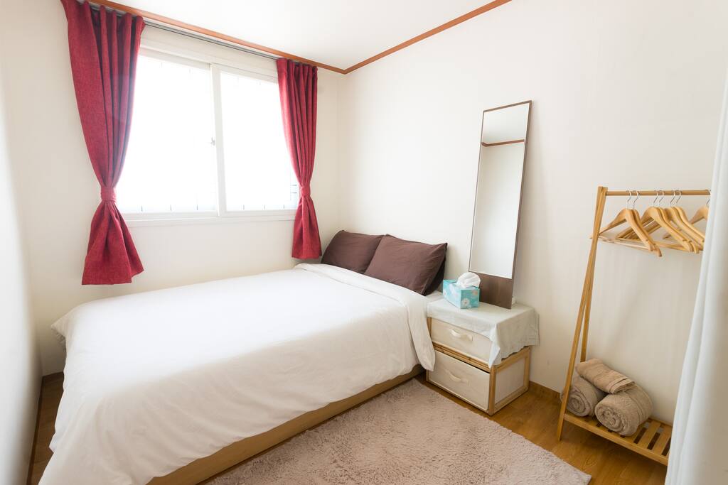 The small bedroom is still plenty spacious. With a double-sized bed, mirror, nightstand, hanger, and plenty of sunlight.