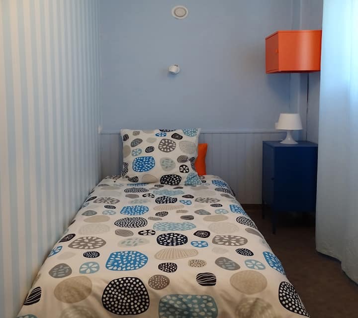 Პატარა საძინებელი 90 × 190 საწოლით (ზეწრები უფასოდ არის მოწოდებული), საწოლთან მდგარი მაგიდა და გარდერობი, რომელზეც ფოტოზე არ ჩანს დასაკიდი სივრცე.