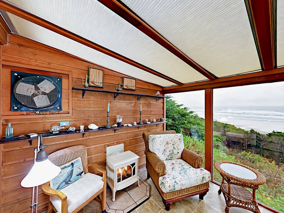 The sunroom off of the master suite features seating, a fireplace, and stunning ocean views through floor- to-ceiling windows.