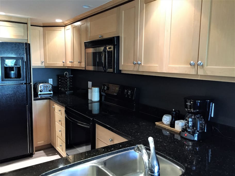 Kitchen with brand new convection range, granite counter tops, and automatic ice & water dispenser.