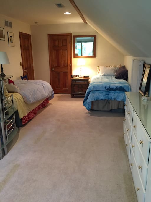 In a cozy bedroom with two twin beds at one end, ...