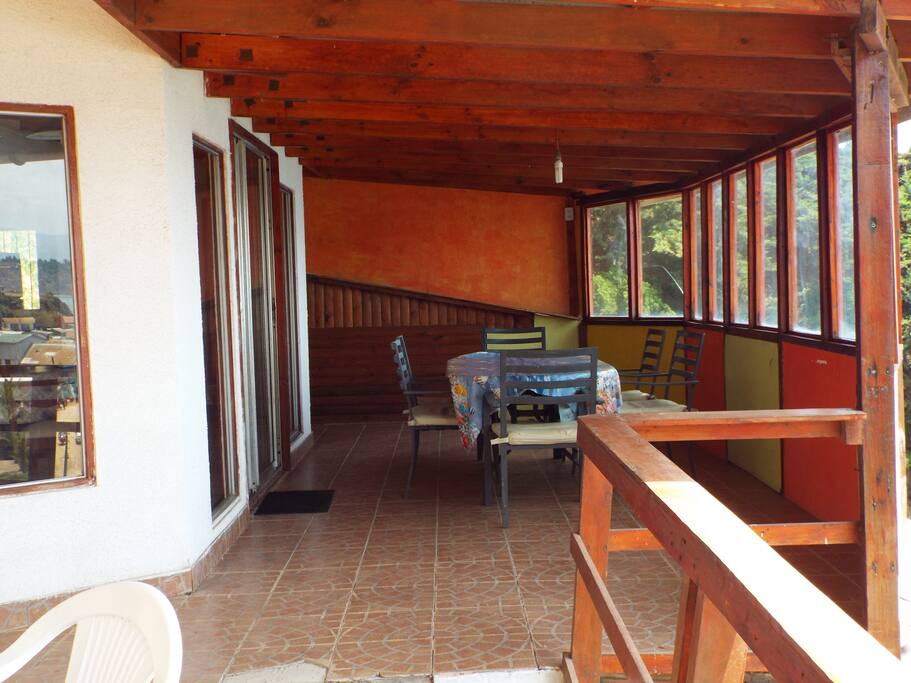 Deck just outside the house with ocean view, table and chairs.