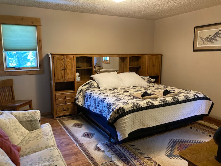 Glavna spavaća soba s privatnim kupatilom, ormarom i ljubavnim sjedalom. TV s velikim ekranom je postavljen na zid s DVD playerom. 