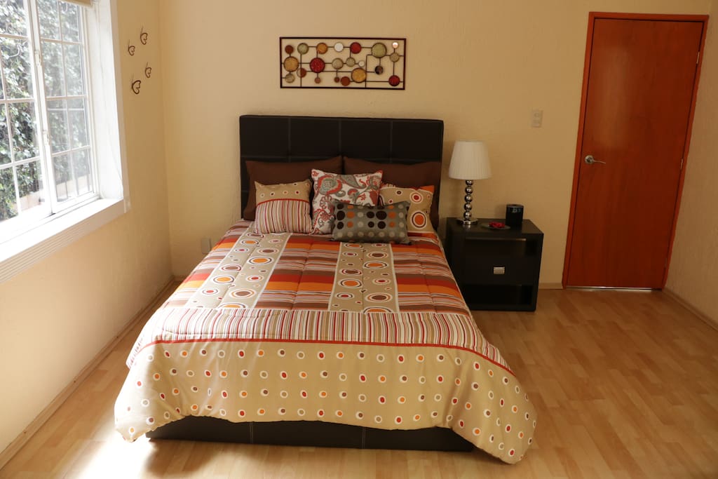 Recámara con cama matrimonial, buró y escritorio.