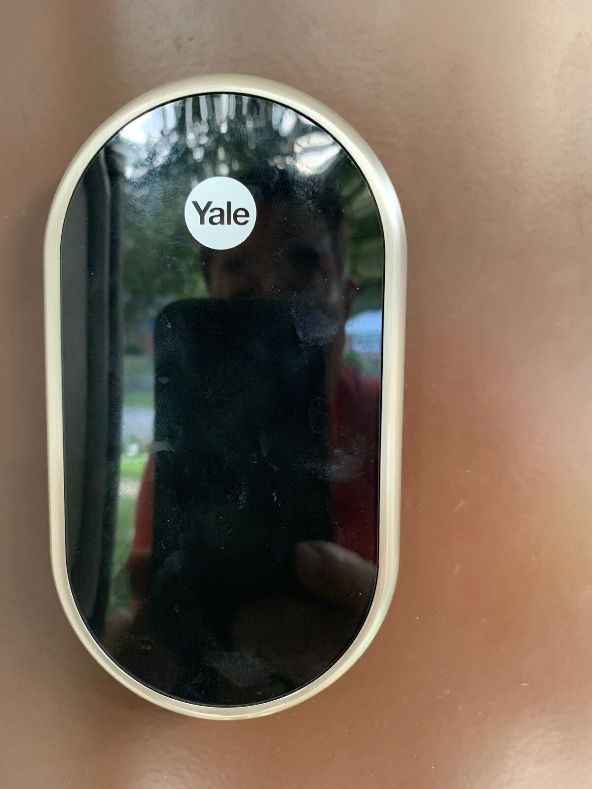 A sleek Yale smart lock is displayed, featuring a modern design with a glossy black finish and metallic accents. The lock's circular shape offers a contemporary look, while its touchscreen interface provides an easy access point for guests.