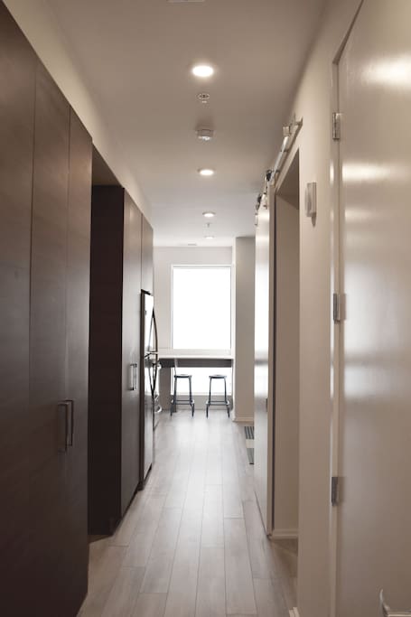The well lit hallway leading you into the living open kitchen, breakfast/dining nook, and living area