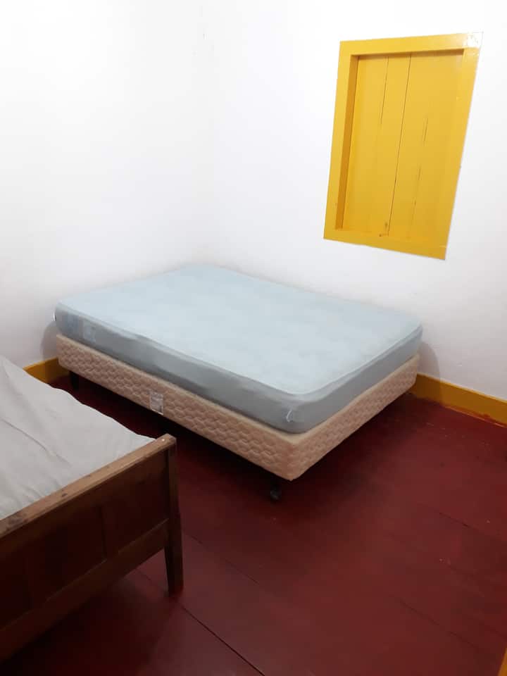 Manželská posteľ a jednolôžko v spálni malého domu.