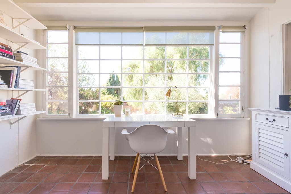 Office/sunroom equipped with lamp, books, stereo and desk