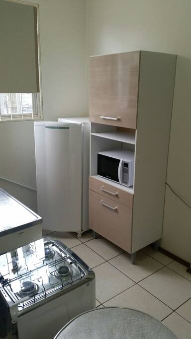 cozinha com armários.
geladeira, microondas, fogão 4 bocas + forno, mesa.