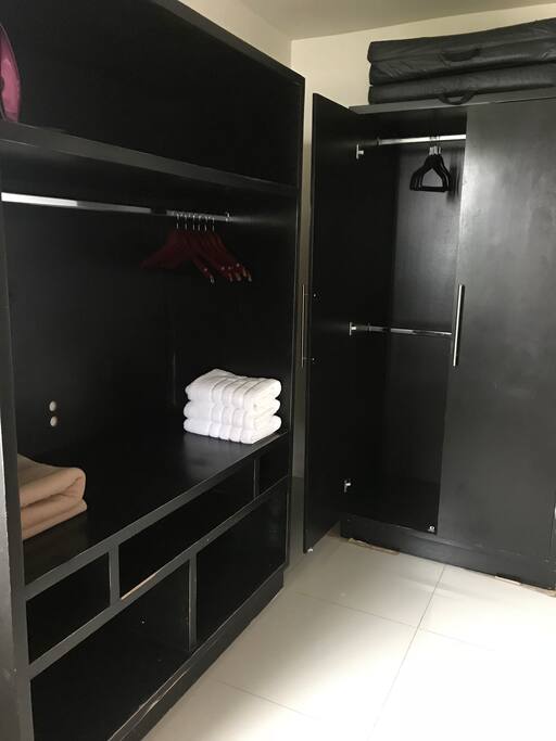 Amplio vestidor dentro de la habitación con plancha, burro de planchar, toallas y suficiente espacio para guardar y colgar ropa.