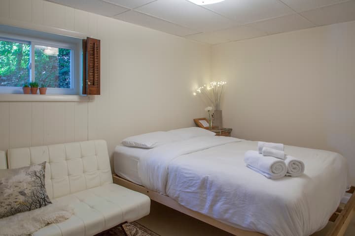 غرفة نوم في الطابق السفلي بسرير بحجم كبير ووسائد منخفضة. على الرغم من أننا نحب الضوء الطبيعي ، إلا أن غرفة النوم هذه رائعة لأولئك الذين لا يحبون الكثير من الضوء للتدخل في نومهم في الصباح لأن المصراع يمكن أن يغلق الضوء تمامًا.