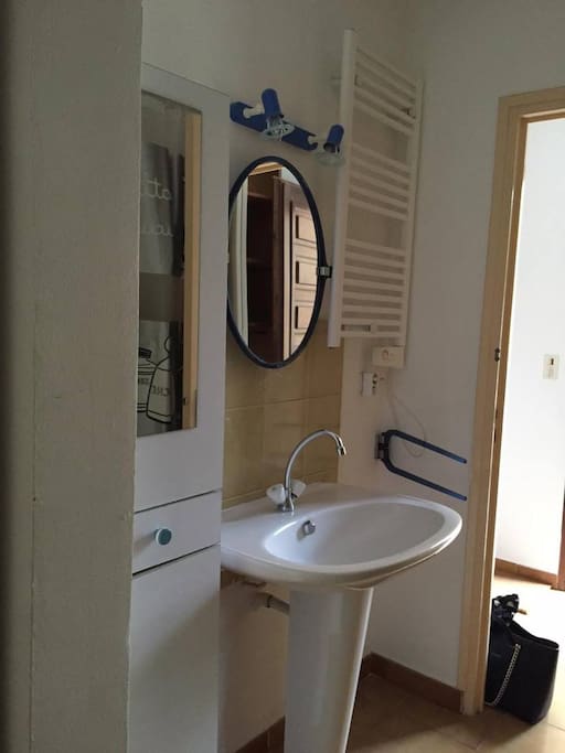 Salle de bain avec baignoire et grand meuble de rangement très propre