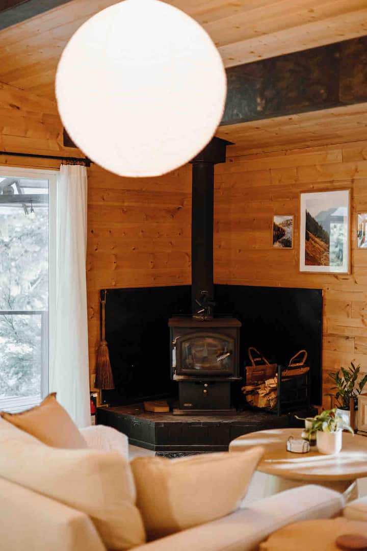 Cozy living room with wood-burning stove, smart TV, and comfy oversized chair and couch.