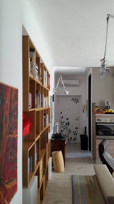 You walk and you turn: here is the entrance door, the wooden library to left and kitchen wall to the right.