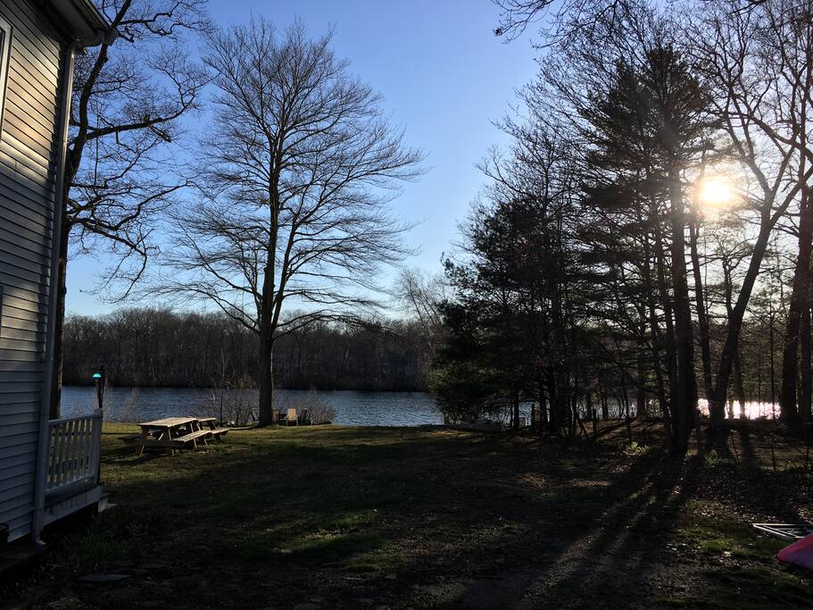 View of the sun setting over Ames Long Pond from the sliding door in the living room and the deck. The beach is along the tree line.