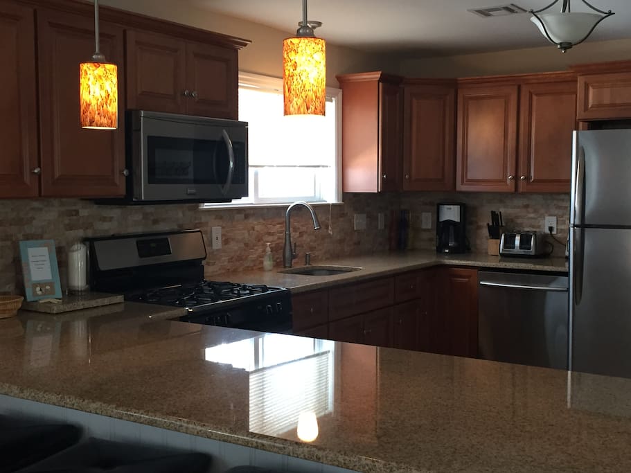 Open concept kitchen and family room with granite countertops and stainless steel appliances.