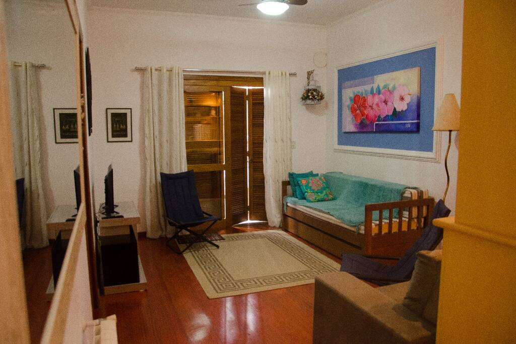 Living com sofa e cama auxiliar com porta que dá para a varanda e churrasqueira privadas.