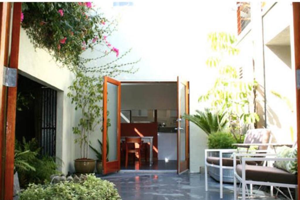 Living and dining connected through lush courtyard