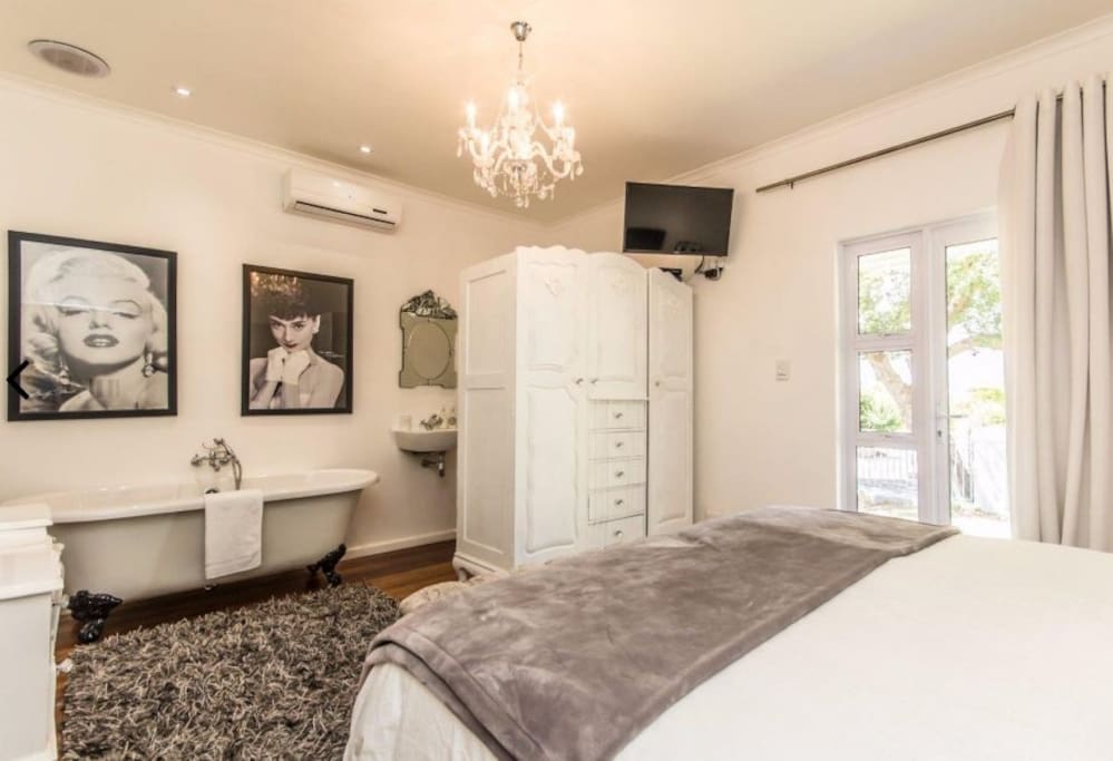 Bedroom 2 has 2single beds or can be a kingsize a bed, aircondioning, TV with all DSTV channels , and en-suite/ open plan bathroom with basin, toilet and Victorian style bath. The bedroom also has its own patio looking out onto the front garden.