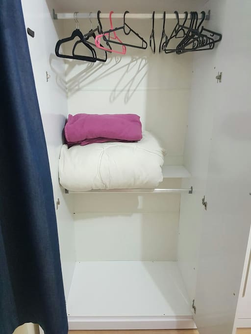 Guarda roupa com cobertores e cabides disponíveis para uso.