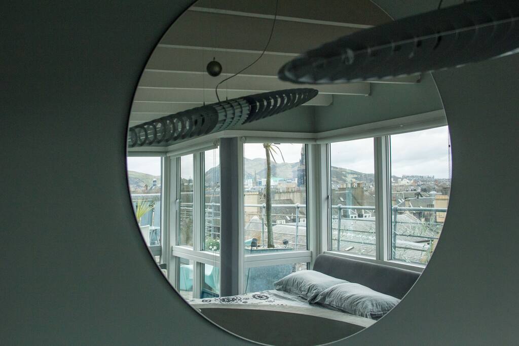 view of the bedroom in mirror at the top of the spiral stairs