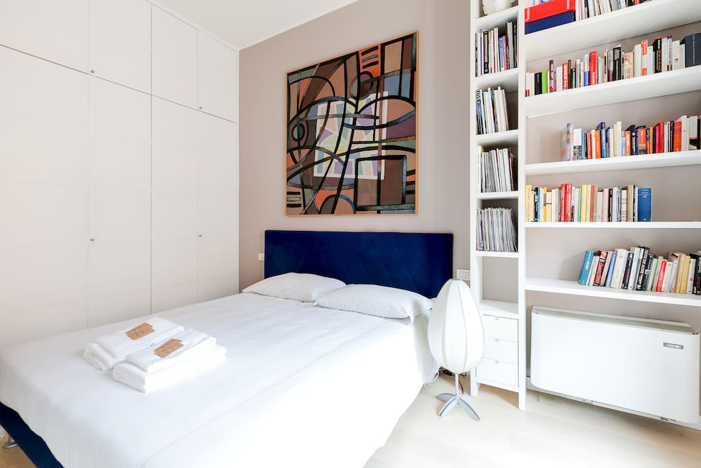 The Bedroom - The comfortable double bed with soft bed-linen and towels & the bookcase