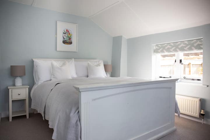 Ave de canto: acogedora habitación con una cómoda cama tamaño queen para 1 con edredón de pato y plumas y almohadas. Ropa de cama de algodón 100%. Disfruta de unas vistas encantadoras sobre el jardín de la cabaña y hacia la iglesia con su pintoresca torre del reloj que suena suavemente.