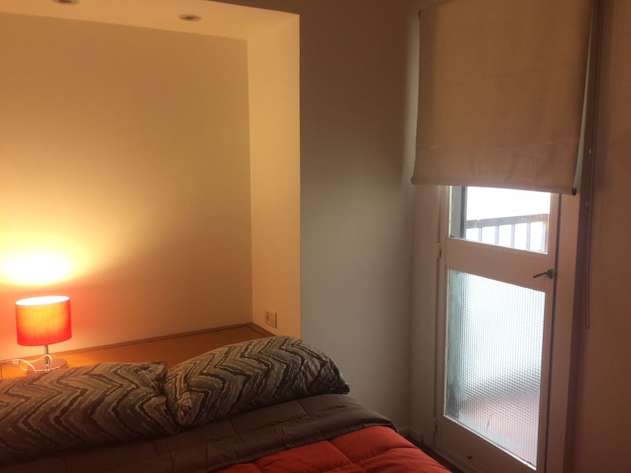 Dormitorio con cama de dos plazas, luz y pequeño balcón. Aire acondicionado.