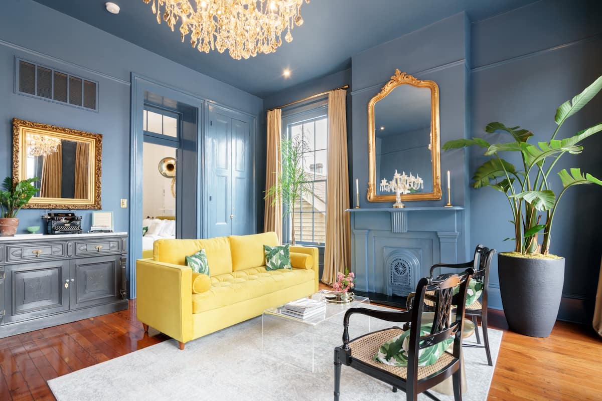 Gorgeous New Orleans AirBNB in the Garden District.  Crystal Chandelier and bright pop of color with a yellow couch.  The slate blue wall paint gives a touch of classy luxury.