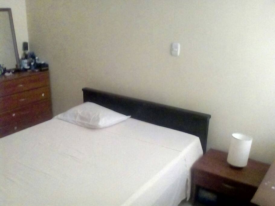 Alcoba con cama matrimonial. Peinadora. Mesita de noche. Ventilador.