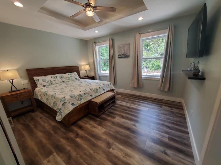 South side master suite with a comfortable king bed, a 65 in. TV, tray ceiling lighting, walk in closet, a private bathroom and a beautiful view of the backyard.