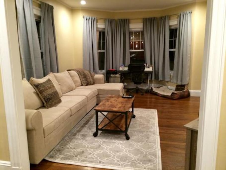 Living Room w/ desk looking out over the park. To the right there is a 60" flat screen TV.