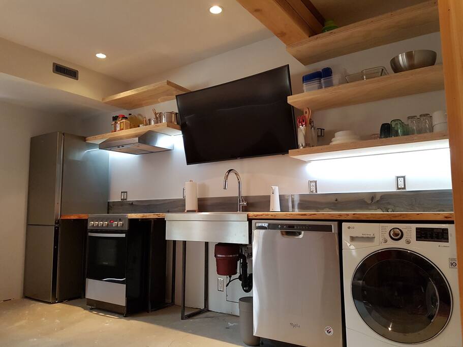 Custom kitchen and media centre, with new appliances and wood and tile detailing. TV viewable from both the living room and bedroom.