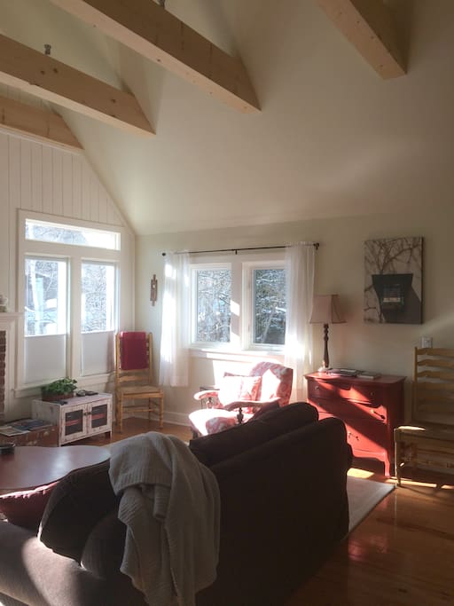 The bright, spacious living room is on the upper level and is surrounded by trees.