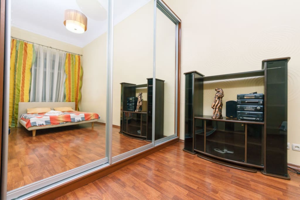 A bedroom with a large built-in closet and a double bed with an orthopedic mattress, with cotton bed linen and towels