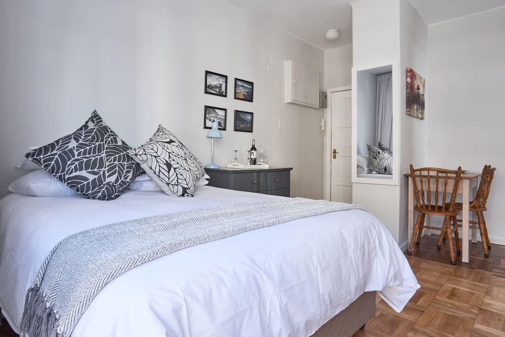 Bed with small dining table and 2 chairs on the right.