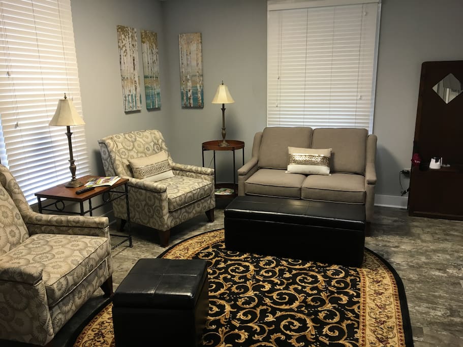 Living area with love seat, chairs, ottomans & TV.