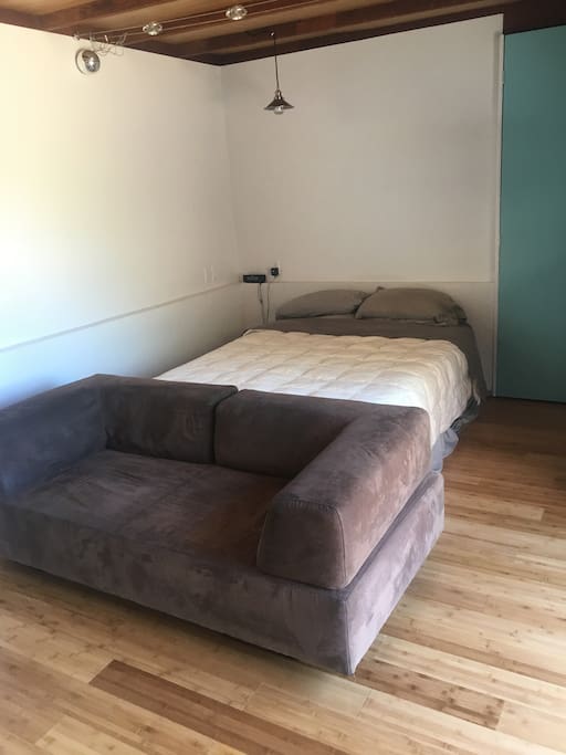Queen Size Bed with small couch in front and hanging lamp with smart Twist bulb for smart phone control and to use as speaker for music