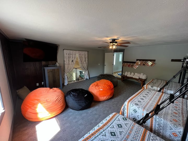 Bunk room with beanbag chairs and a 65” flatscreen tv.