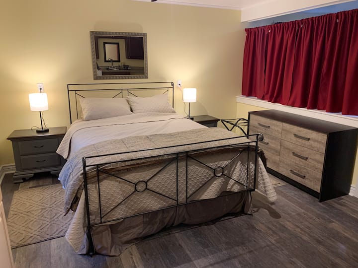 Dhoma e gjumit e katërt, me divan në anën tjetër të perdeve dhe murit ndarës.