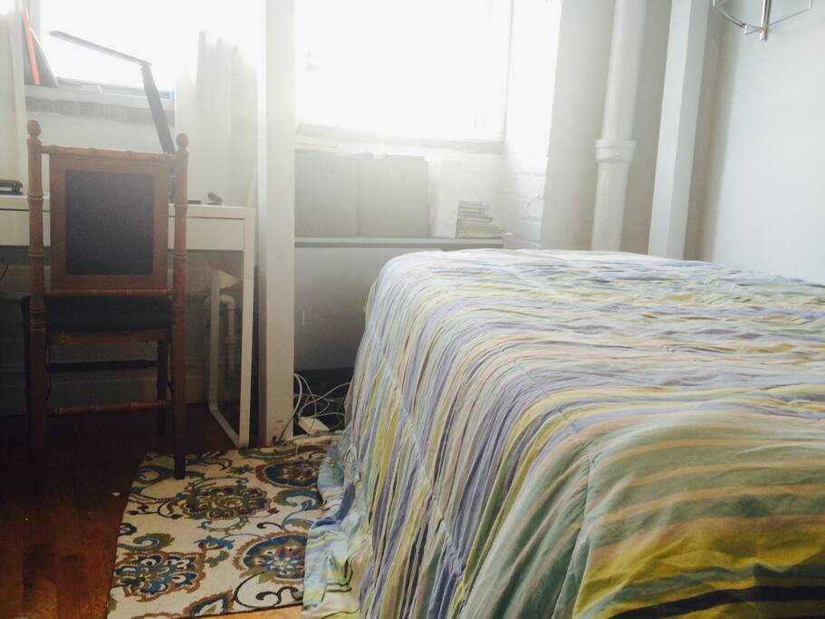 Sunny bedroom with three windows and curtains.