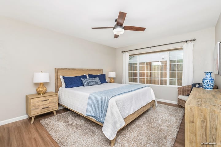 Главната спалня със самостоятелна баня има суперголямо двойно легло, две крайни маси с маси, скрин и смарт телевизор.