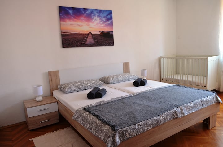 Apartment 1: bedroom with double bed and cot, ceiling fan + standing fans available, air conditioning is in the corridor