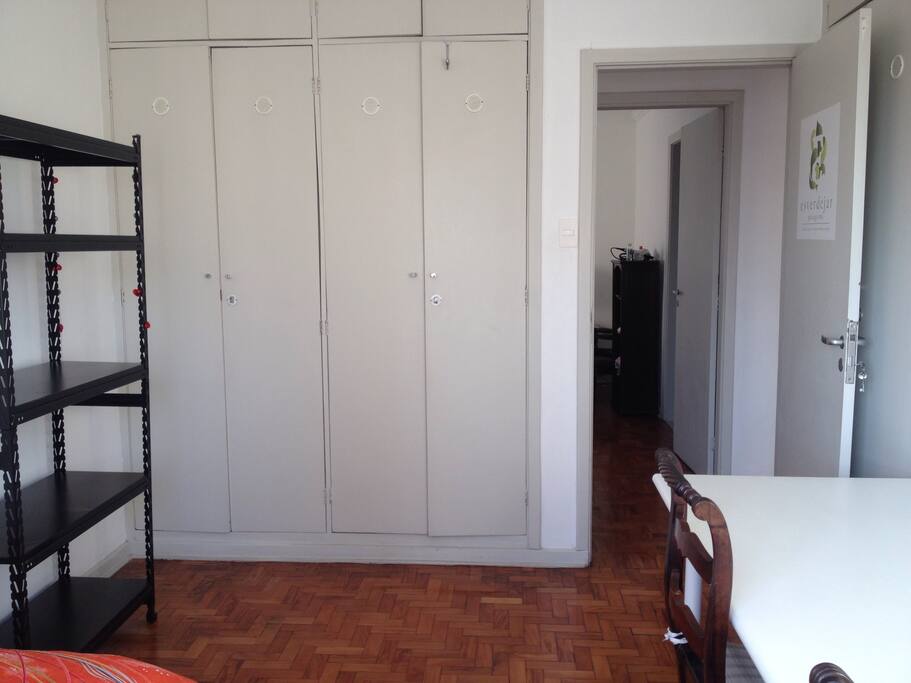 Este é o quarto disponível, tem uma bicama de solteiro, estante, um armário amplo e uma mesa grande de trabalho