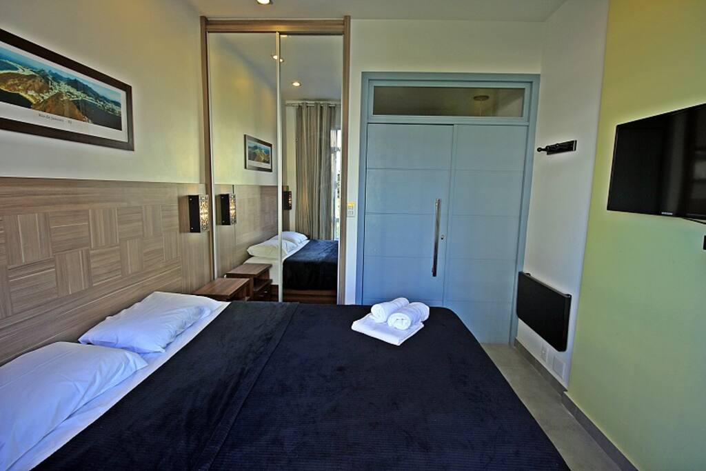 Quarto com cama de casal, asr condicionado, TV LCD e armário.