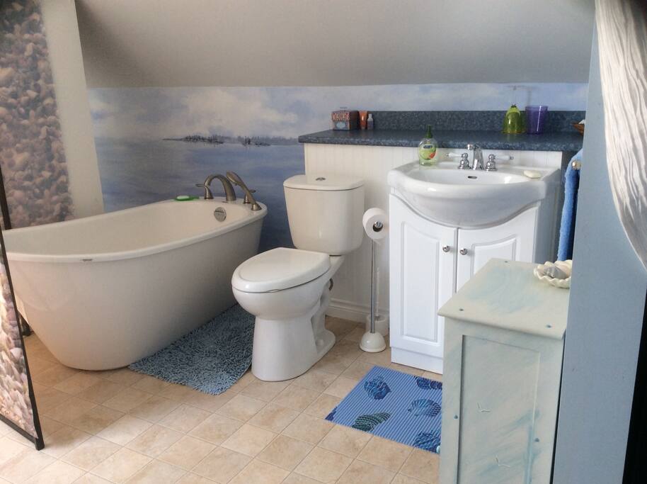 Luxurious private bath with gorgeous seaside view of hand painted wall mural. Hand held shower option.