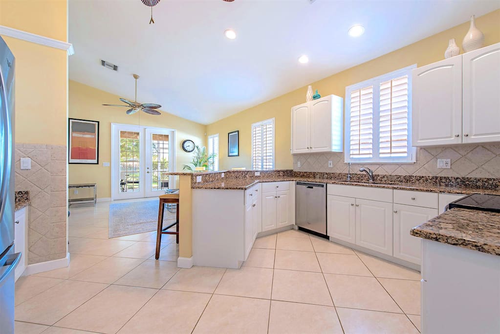 Fully equipped kitchen with large fridge, high ceilings and lots of natural light. View towards the living room.