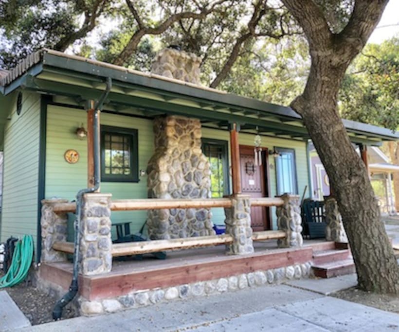 The exterior has a rustic 'log cabin' appearance with a faux stone fireplace/chimney, a front porch with adirondack chairs where you can sit, relax and marvel at the rural surroundings and gentle sounds of nature.
